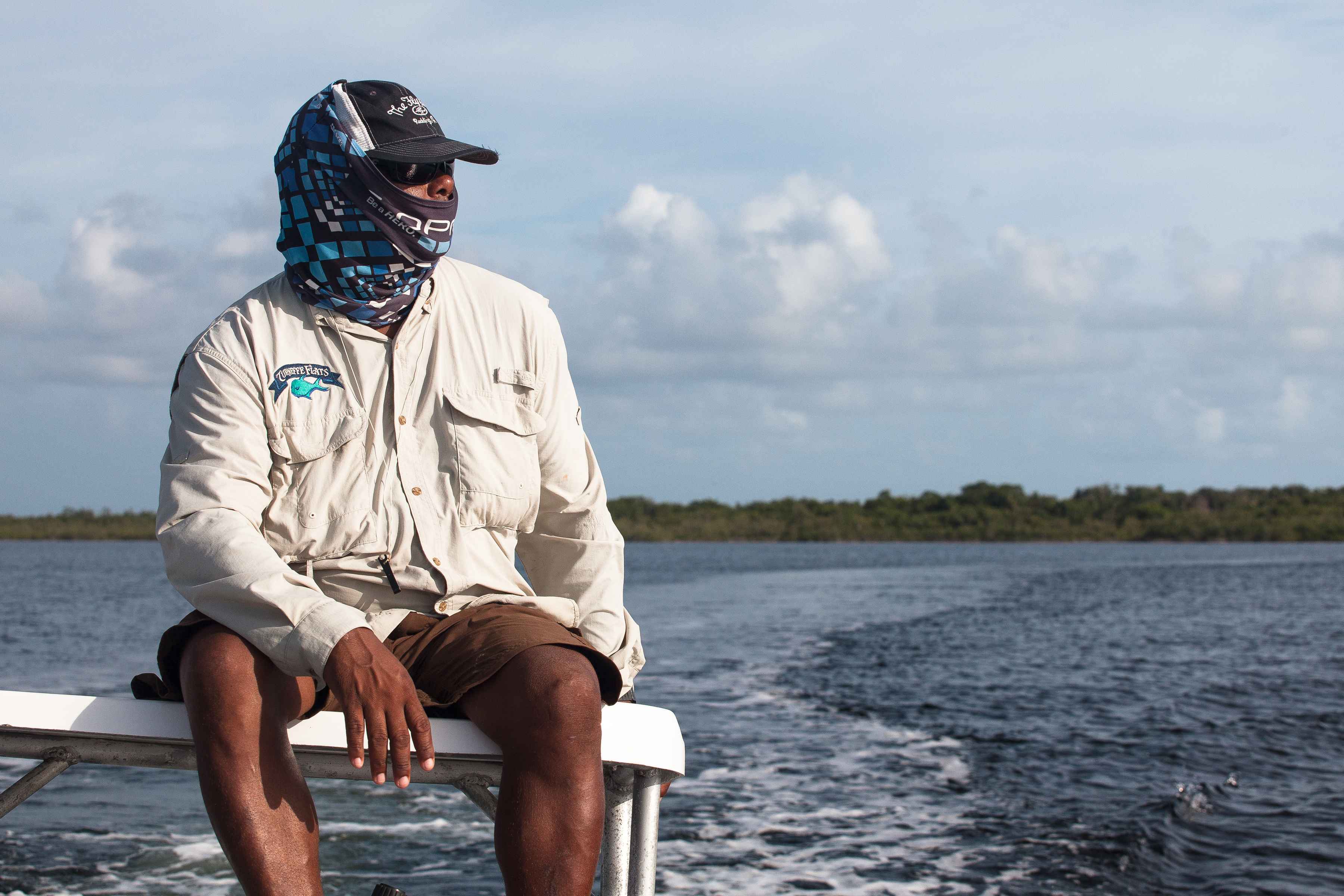 Guide Daniel scouts the lagoon for bonefish under the sunnier skies of an earlier day (photo: Chad Shmukler). Scouting Permit - Belize