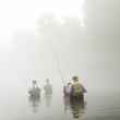 crowd of anglers fly fishing stream